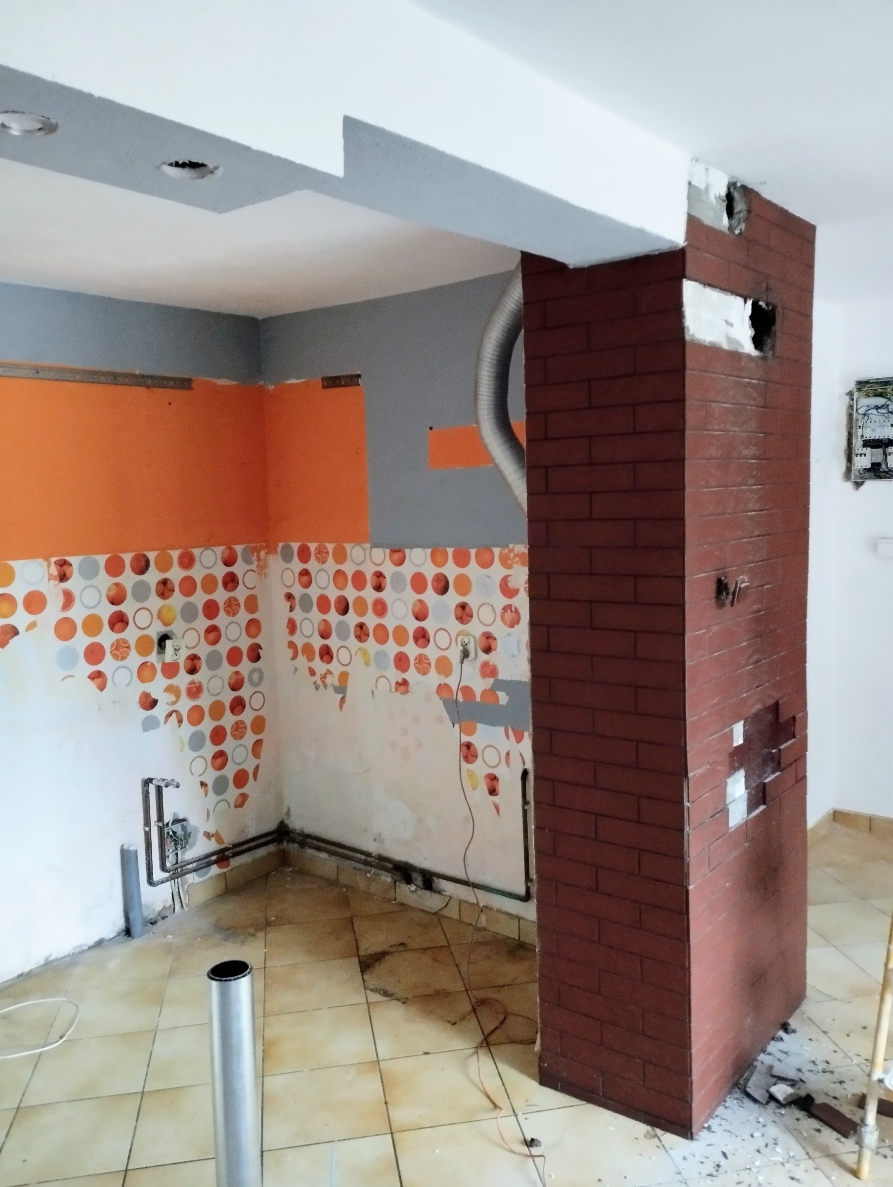 Salon z kuchnią przed remontem – widoczny komin i strefa kuchenna.