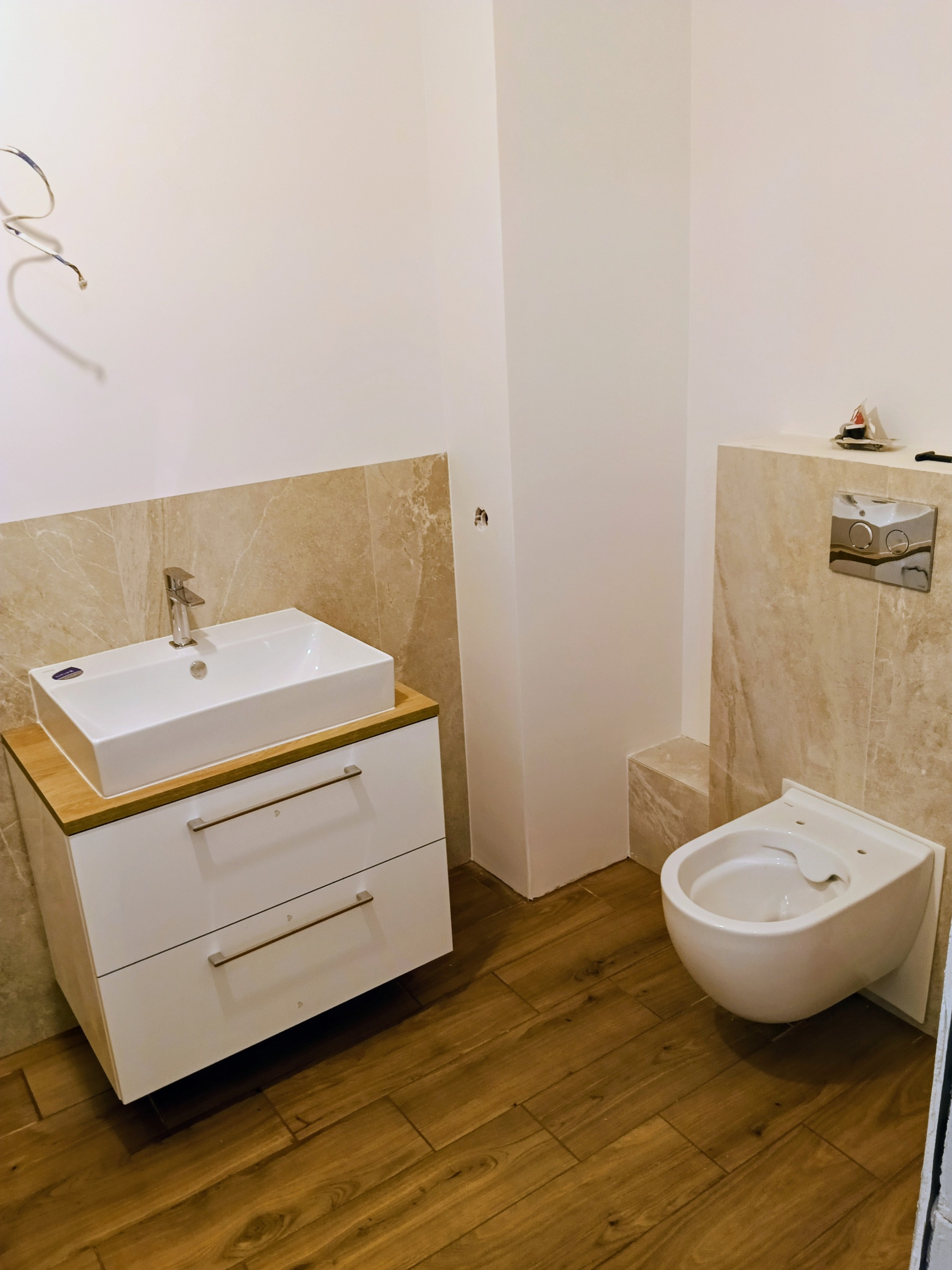 Łazienka po remoncie – umywalka, WC i gresowa lamperia.