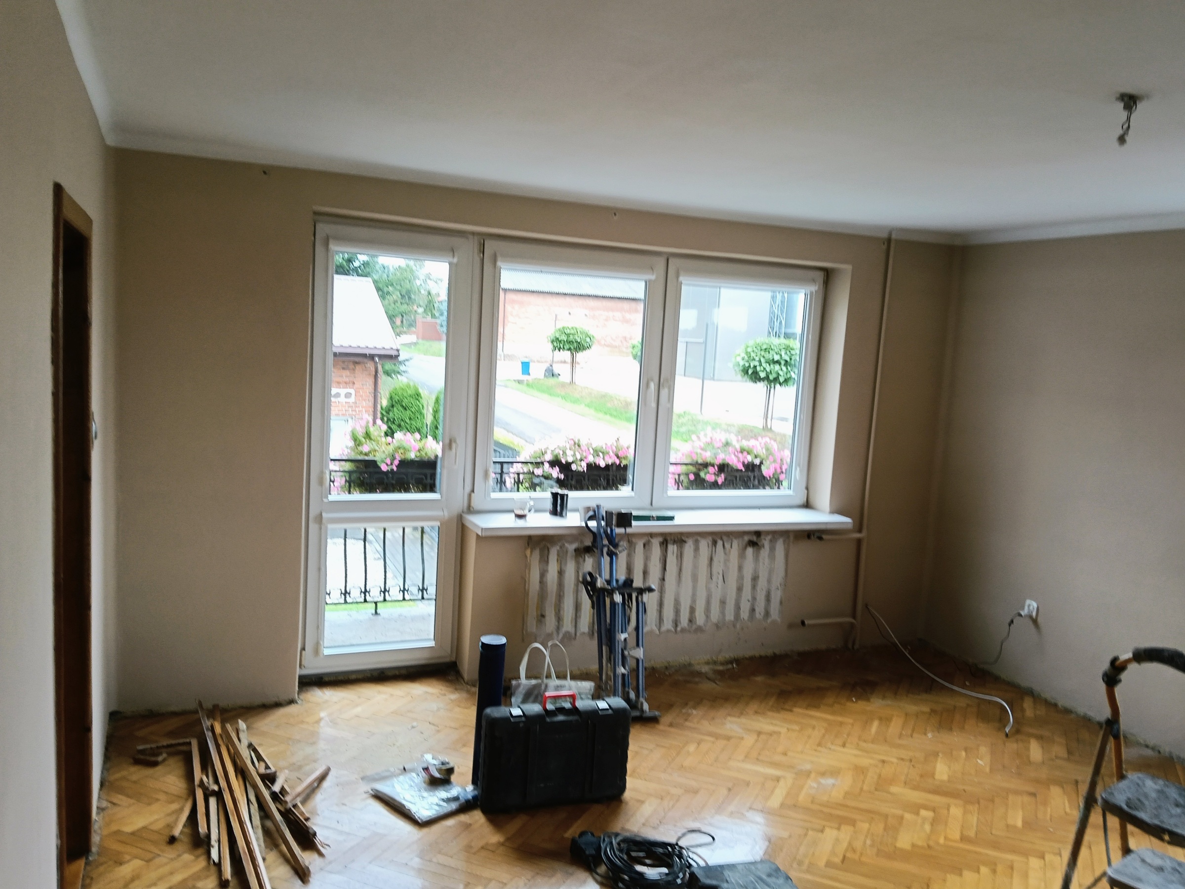 Salon przed odświeżeniem – widok na okno i ściany.