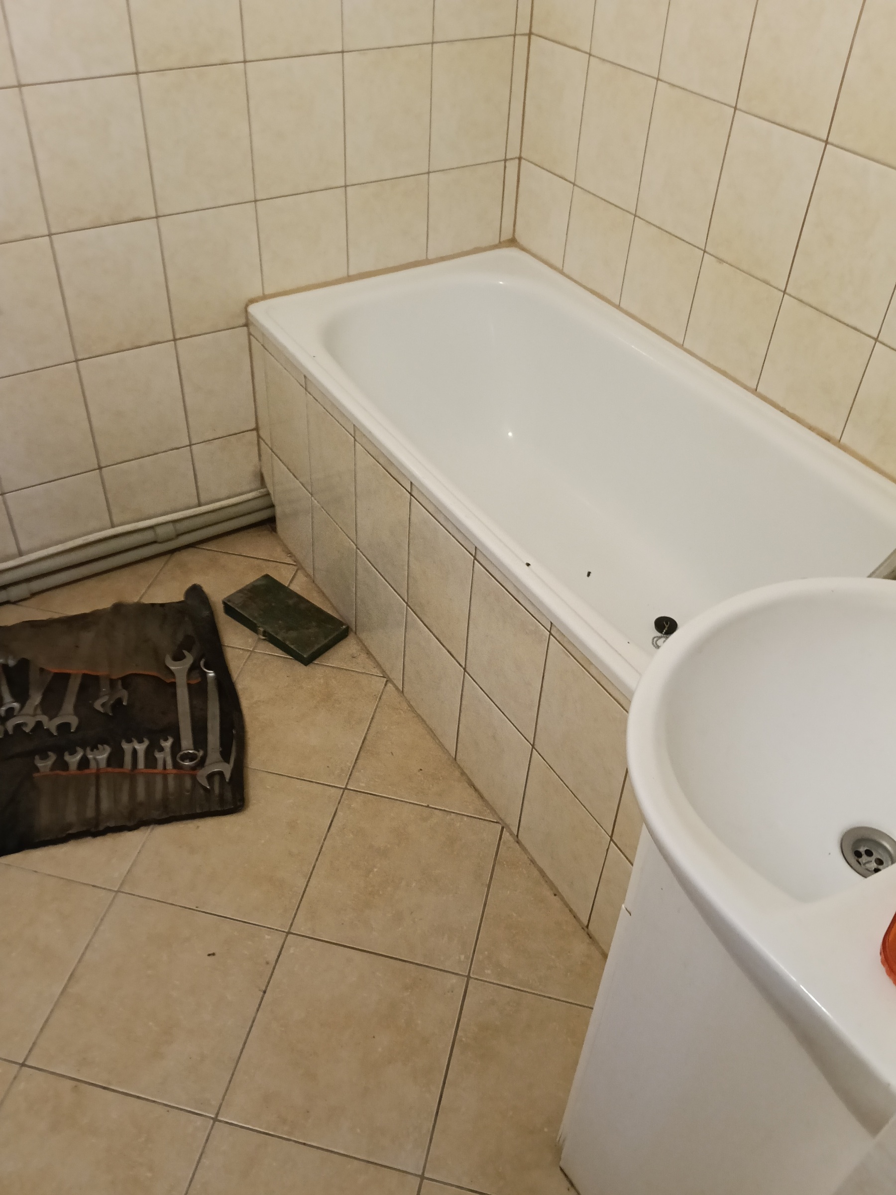 Łazienka przed remontem – wanna, umywalka i stara podłoga.